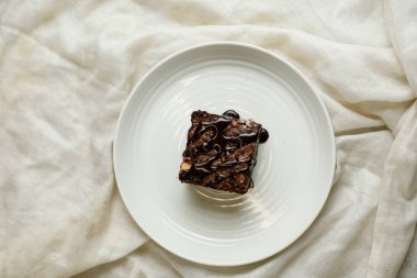 Tabakta servis edilen çikolatalı Brownie arka planda pişmiş kafe yemeklerinin peçetesinin üstünde izole bir şekilde duruyor.