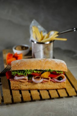 Ciabatta Füme Jambonlu Sandviç ahşap üzerine izole edilmiş mayonez sosu ve patates kızartması kovası ile gri arka planda İtalyan fast food manzarası