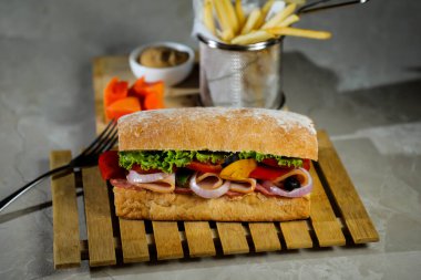 Ciabatta Füme Jambonlu Sandviç ahşap üzerine izole edilmiş mayonez sosu ve patates kızartması kovası ile gri arka planda İtalyan fast food manzarası