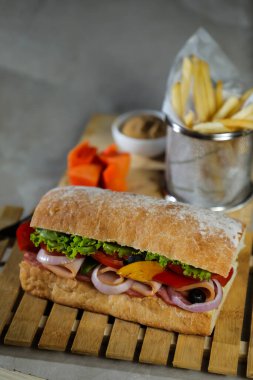 Ciabatta Füme Jambonlu Sandviç ahşap üzerine izole edilmiş mayonez sosu ve patates kızartması kovası ile gri arka planda İtalyan fast food manzarası