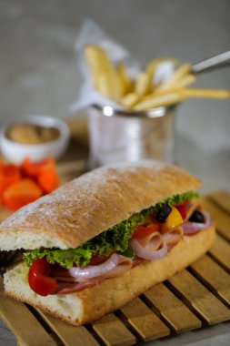 Ciabatta Füme Jambonlu Sandviç ahşap üzerine izole edilmiş mayonez sosu ve patates kızartması kovası ile gri arka planda İtalyan fast food manzarası