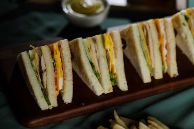 Tahtadan izole edilmiş mayonez sosu ve İtalyan fast food arka planında patates kızartması tabağı manzaralı çeşitli Club Sandviç.
