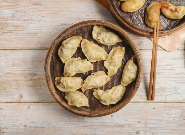 Handmade steamed dumplings and fried dumpling or momo served in wooden dish with chopsticks isolated on table top view Japanese food