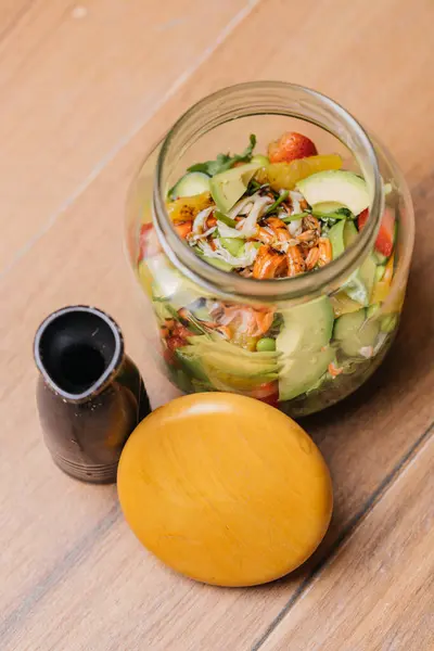 Shakin Salad in Jar or mason salad jar with strawberry, cucumber, tomato, carrot and lettuce leaf served in dish isolated on table side view of healthy organic salad