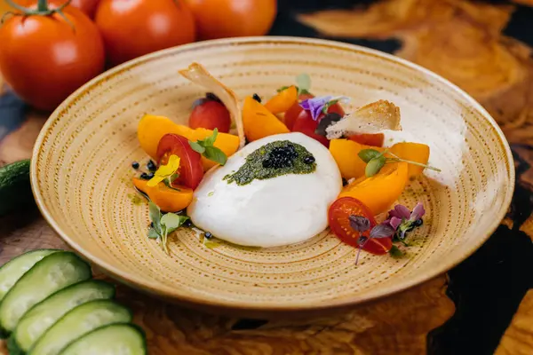 Burrata salad with cherry tomato, cucumber, strawberry, flower and leaf served in dish isolated on table side view of healthy organic salad