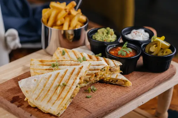 Chicken Quesadillas taco wrap slice with chili sauce and french fries bucket served on wooden board isolated on table top view of arabic fastfood