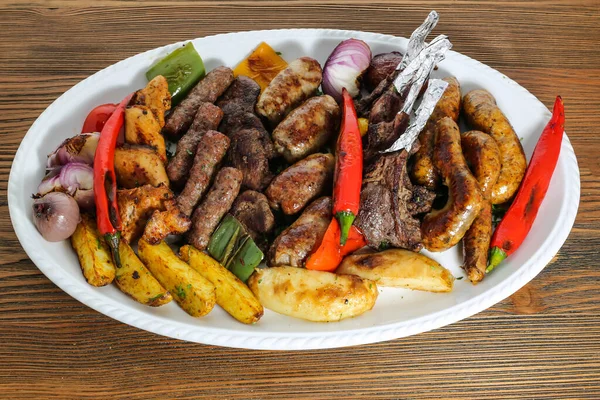 Mix grill family platter tikka kabab, lamb chop, meat kebab, chicken, beef, mutton, potato veggies, tomato and onion served in dish isolated on table top view of arabic food
