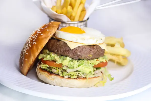 beef burger with sunny side up egg and french fries bucket served in dish isolated on table side view of arabic food