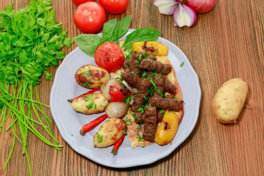 Kofta kebap fareli et kebabı, domates, soğan patatesi ve kişniş arap yemeğinin üst katında izole bir şekilde servis edilir.