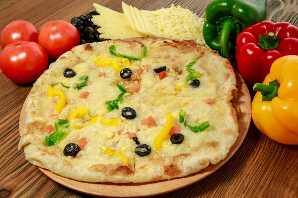 Mix cheese and vegetable pizza with bell pepper, tomato and black olive served in wooden board isolated on table side view of arabic food