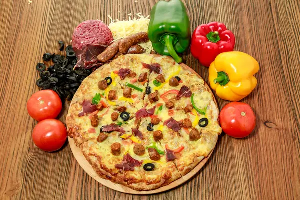 Mix meat pie sausage pizza with bell pepper, tomato and black olive served in wooden board isolated on table side view of arabic food