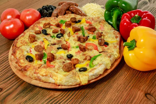 Sausage and minced meat pizza pie with bell pepper, tomato and black olive served in wooden board isolated on table side view of arabic food