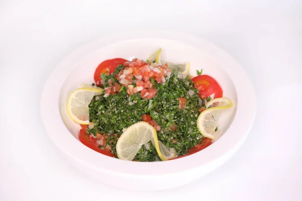 TABOULEH Salad eith tomato, leaves, and lemon slice served in dish isolated on background side view of arab food
