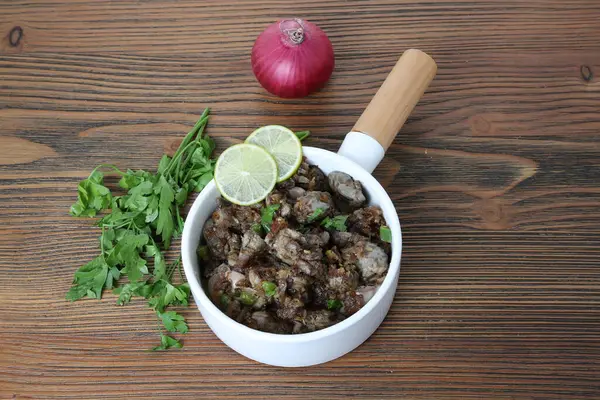Spicy Chicken liver with onion, coriander and lemon slice served in dish isolated on table side view of arabic food