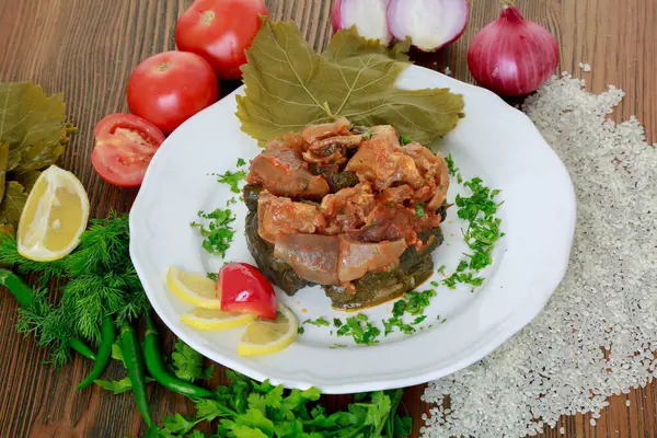 vine leaves casserole with tomato, onion, rice, coriander, lemon slice and green chilli served in dish isolated on wooden table side view of arabic food