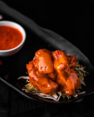 Biber soslu dinamit gibi tavuk, ahşap masa manzaralı Arap yemeği tabağında servis edilir.