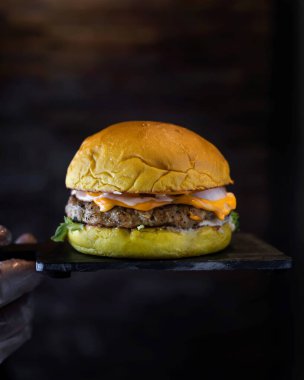 Klasik eritilmiş peynirli tavuk burgeri, mayonez ve marul yaprakları, ahşap masa tarafından izole edilmiş, ahşap masa başında servis edilir.