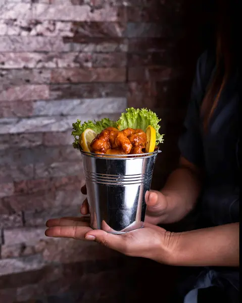 Dynamite Shrimp Bucket holding in hand with say sauce, lemon slice and lettuce leaves served side view of arabic food