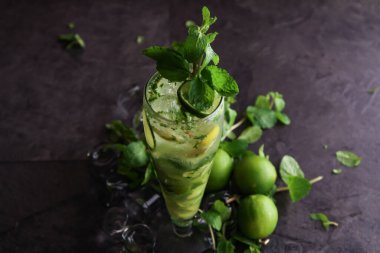 Tek kullanımlık bardakta servis edilen limon naneli mojito. Sağlıklı içeceklerin olduğu masa kenarında izole edilmiş.