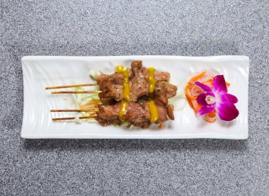 Pork satay çubukları, gri arka planda Hong Kong yemeklerinin üst görüntüsünde servis edilir.