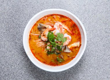 Tom yum kung çorbasında Tayland pilavı eriştesi. Gri arka planda izole edilmiş Hong Kong yemeğinin üst görüntüsünde servis ediliyor.