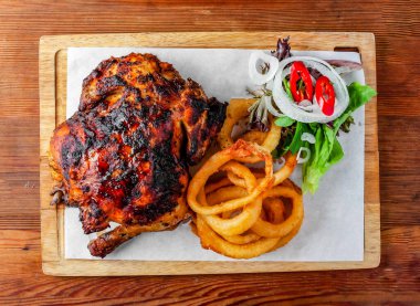 Soğan halkaları ve salatalı ızgara tavuk ahşap masa üzerinde Hong Kong yemeklerinin üst görüntüsünde izole edilmiş ahşap tahta servis edilir.