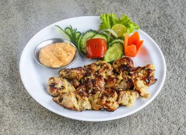 Hint baharatlarının gri arka planında servis edilen salata ve mayonez soslu tavuk malai boti tikka kebabı.