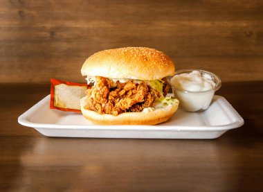 Ketçap ve mayonez soslu çıtır tavuk zencefilli hamburger. Ahşap arka planda Hint baharatları ve Pakistanlı yemeklerinden izole edilmiş.