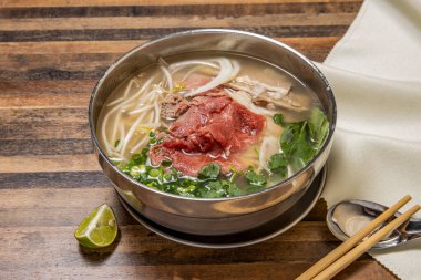 Hanoi nadide sığır eti soslu soğan, erişte, yeşil soğan, limon ve kişniş Hong Kong fast food 'un ahşap masasında izole bir şekilde servis ediliyor.