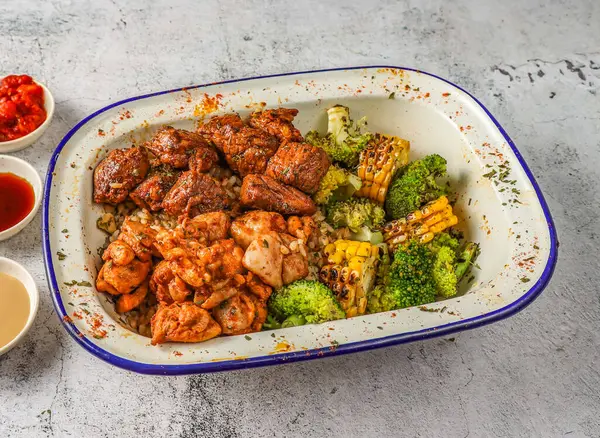 Spicy chicken and tenderloin with fried rice, grilled corn and broccoli served in isolated on grey background top view of singaporean food