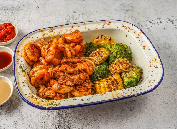Grilled shrimp and chicken with noodles, grilled corn and broccoli served in isolated on grey background top view of singaporean food
