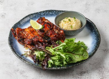 Chao ta ızgara domuz pirzolası, plai pilavı, limon ve yeşil yapraklarla servis edilen gri arka plan manzaralı Singapur yemeği.