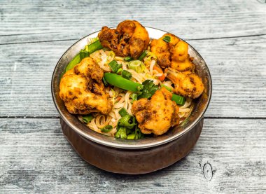 Gobi eriştesi veya kızartılmış karnabahar eriştesi, ahşap masaya izole edilmiş, Hint baharatlı yemeklerinin üst görüntüsünde servis edilir.