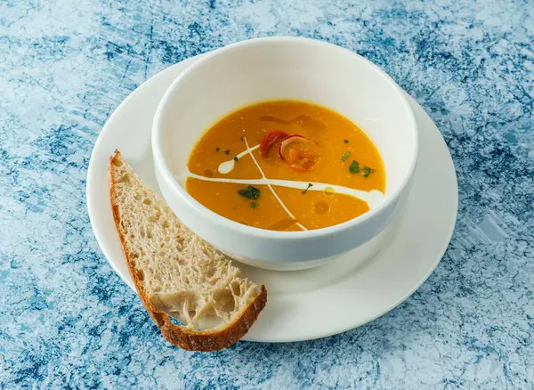 イタリア料理のバックグラウンドトップビューに分離されたボウルにパンを添えたカボチャースープ — ストック写真