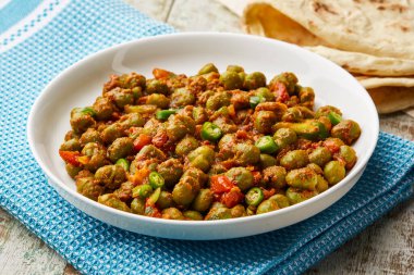 Masala bezelyesi ya da baharatlı matar yeşil fasulye. Domates ve yeşil biberli. Masada servis edilen yeşil biber.