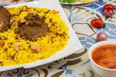 Masadaki Arap yemeklerinin üst görüntüsünde, kaju fıstığıyla servis edilen et Quzi veya Ghozi biryani pilavı.