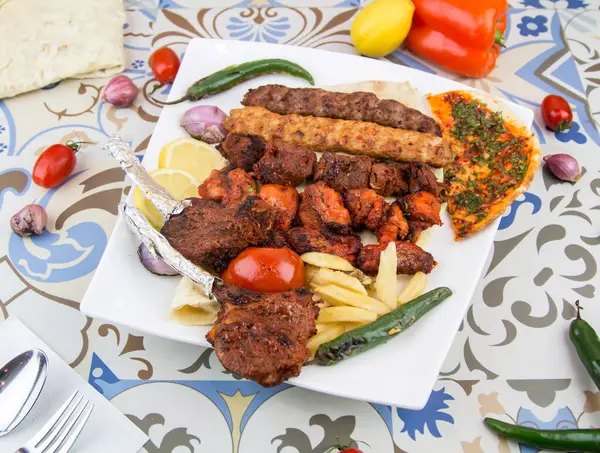 Tikka boti ve kebap ile karışık ızgaralar. Tavuk, biftek, kuzu eti, kuzu eti. Masada servis edilen kuzu bbq tabağı.