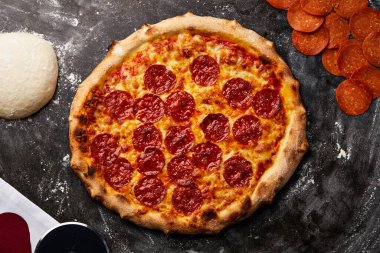 Koyu arka planda izole edilmiş klasik Pepperoni Pizza İtalyan fast food aperatiflerinin üst görüntüsü.