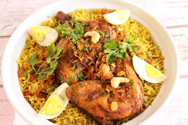 Spacial Chicken Quzi veya Ghozi kabsa mandi pilav pulao kızarmış soğan, kaju fıstığı ve haşlanmış yumurta ahşap masa üstü manzaralı baharatlı yemekler.
