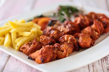 SHISH TAWOOK tikka kebap ve patates kızartması ve salata izole edilmiş ahşap masa üzerinde servis edilen tandır ızgara bbq gıda üst görünümü