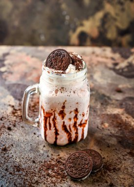 Çikolatalı ve kremalı Oreo Milkshake. Kavanozda servis ediliyor. Sağlıklı içeceğin koyu arka planında.