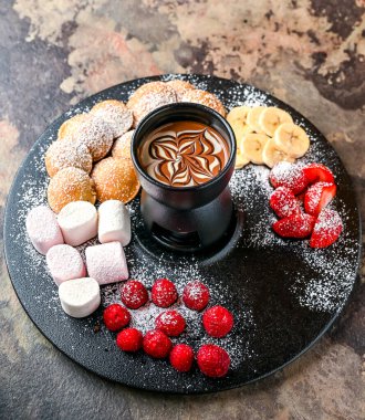 Çilekli, ahududulu ve muzlu çeşitli çikolatalı kokteyller. Koyu arka planda, kafede servis edilen tatlı yemeklerinin üst tarafında.