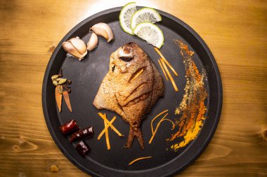 Kızarmış Pomfret Balığı ya da limon dilimli Rupchanda Fry ahşap arka planda izole edilmiş Hint baharatları, bangladeş ve Pakistan yemekleri.