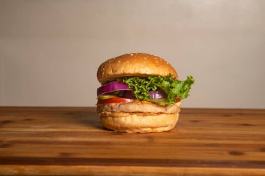 Pastırmalı klasik tavuk peynirli burger ahşap masaya izole edilmiş sağlıksız Fransız abur cuburu manzarası.