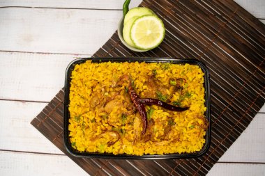 Achari tavuğu khichuri biryani pilavı salatalık ve limon dilimi ile servis edilir ahşap masa üzerinde bangladeş ve Hint baharatlı öğle yemeği manzarası