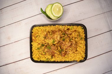 Tavuklu khichuri biryani pilavı, salatalık ve limon dilimli ve ahşap bir masada servis edilmiş. Bangladeş ve Hint baharatlı öğle yemeği manzarası.