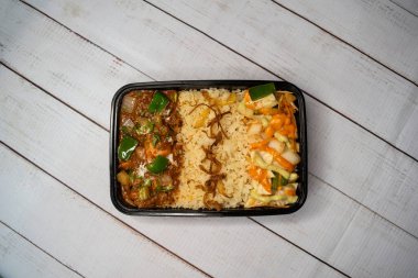 Tavuk tikka masala ile pulao biryani pilavı salatalık, sos ve limon dilimi ile servis edilir ahşap masa üzerinde izole edilmiş Bangladeş ve Hint sokak yemekleri