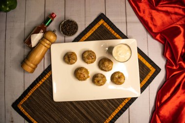 Doldurulmuş mantar, karides köfteli köfte soslu, karabiberli ve sarımsaklı biberli sos peçete görünümlü, ahşap masa üzerinde servis edilen İtalyan yemeği.