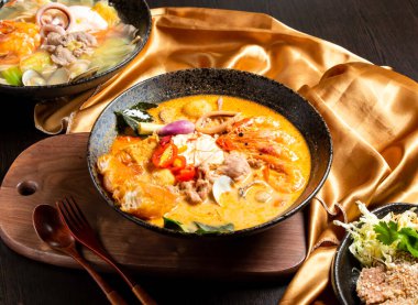 Ahşap tahta güvertede, Asya yemeği manzarasında servis edilen çatal ve kaşıkla deniz ürünleri ve tavuk rostosu.