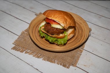 Salatalıklı, domatesli, salatalıklı ve peçeteli bangladeşli yemek masasında servis edilen klasik sığır eti burgeri.